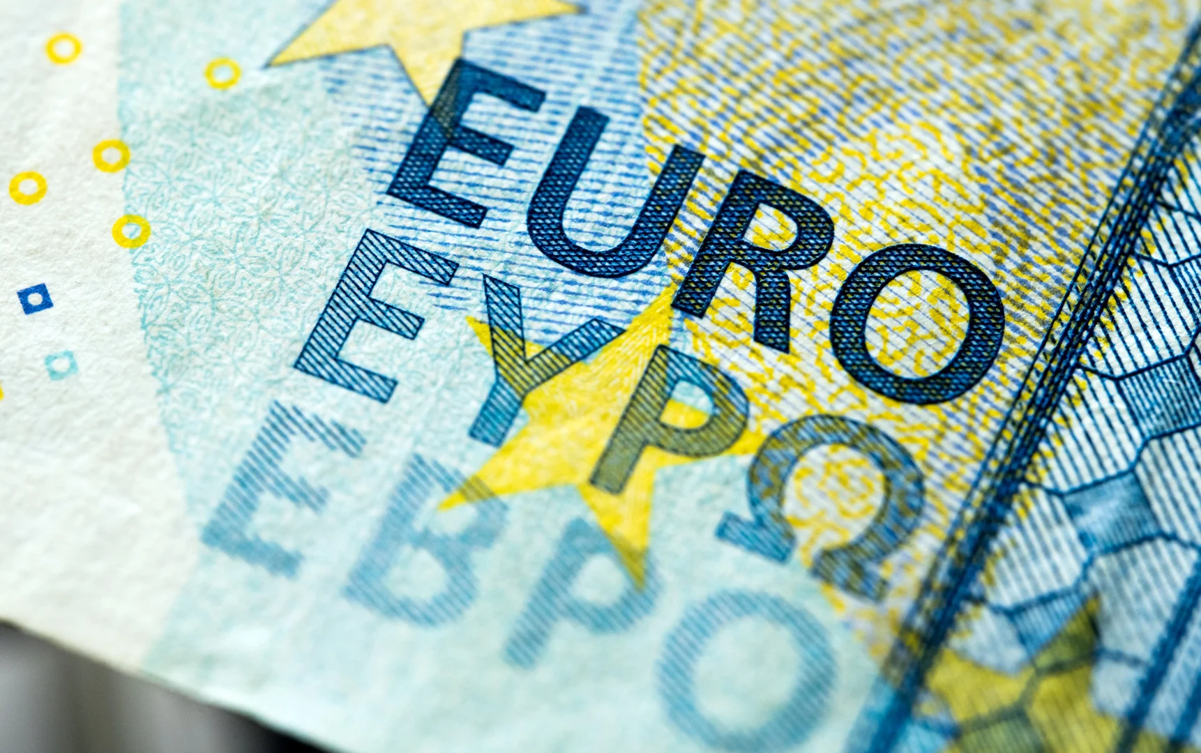 Eine Wissenschaftlerin und ein Wissenschaftler arbeiten hinter einer Glasfassade und mischen Chemikalien mit Großgeräten.