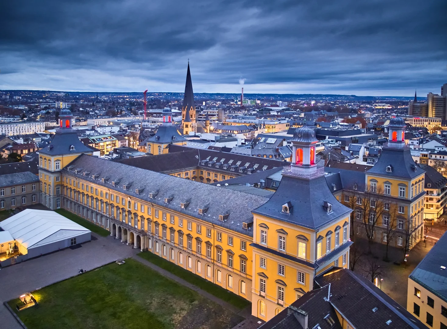 Eine Wissenschaftlerin und ein Wissenschaftler arbeiten hinter einer Glasfassade und mischen Chemikalien mit Großgeräten.